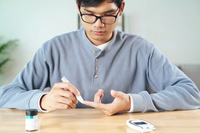 Homme asiatique utilisant une lancette sur le doigt pour vérifier le niveau de sucre